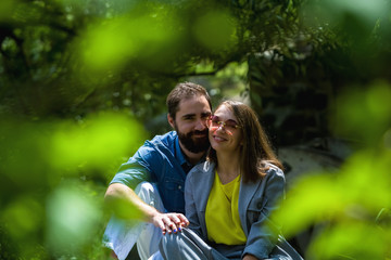 The young and modern loving couple sits among greens in the park. positive emotions. Happiness. Family.