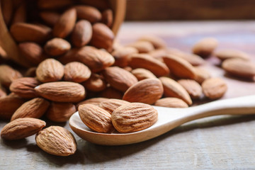 Almond nuts in wooden spoon on rustic background.