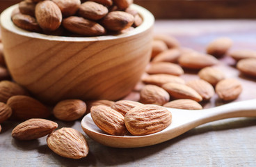 Almond nuts in wooden spoon on rustic background.