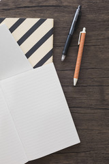 Elevated view of pen; notebook on wooden desk