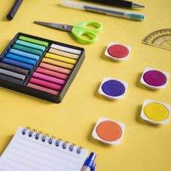 Naklejka premium Close-up of multi colored watercolor paint and stationeries on yellow background