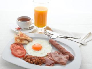 Desayuno inglés con huevos, tomate, beicon, té y zumo de naranja.  Spanish breakfast, egg, sausages, bacon, tomato, orange juice and tea