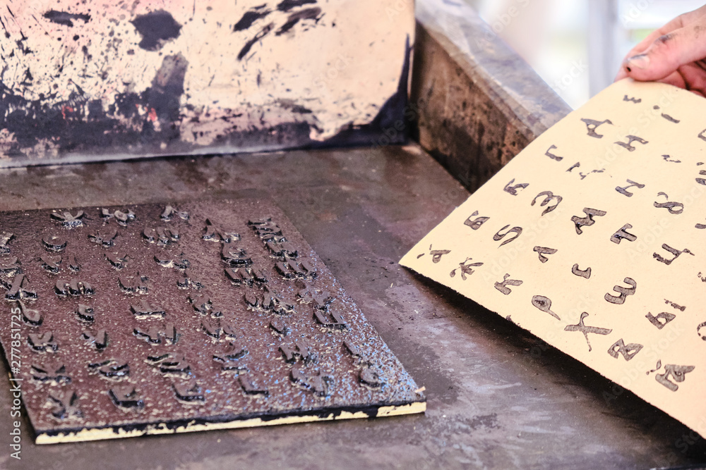 Fototapete a man takes a printed sheet of paper. cyrillic alphabet for printing in vintage style. printing book