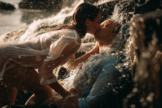 A couple during lovemaking next to a waterfall.