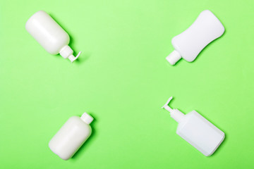 Set of White Cosmetic containers isolated on green background, top view with copy space. Group of plastic bodycare bottle containers with empty space for you design