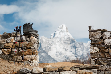 Everest trekking. Trekking boots, trekking poles and a cup in focus. Mountain Ama Dablam in the...