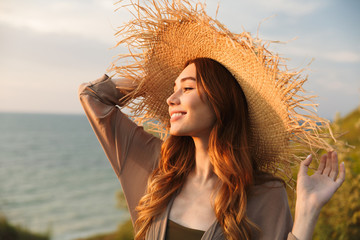 Beautiful young pretty woman in hat posing outdoors near sea on the beach.