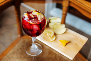 A glass of refreshing cold sangria with ice on a glass table.