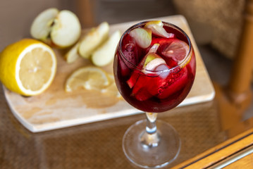 A glass of refreshing cold sangria with ice on a glass table.