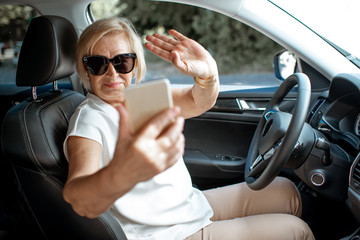 Senior business woman talking with smart phone while driving a car. Concept of an active people...