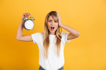 Screaming sad young blonde woman posing isolated over yellow wall background dressed in white...