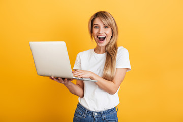 Positive optimistic emotional young blonde woman posing isolated over yellow wall background...
