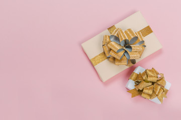 Gift box wrapped in pastel  paper with gold  ribbon on black surface. Top view with copy space.