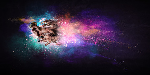 Hands holding champion cup on colourful splashes background. Mixed media