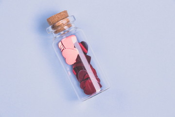 Naklejka premium Flat lay. Confetti in the form of heart in a decorative bottle on a light blue background.