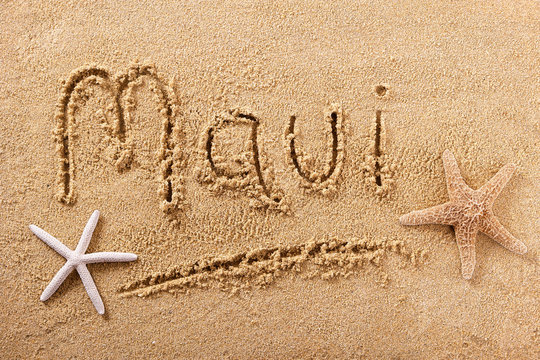 Maui word written in sand sign writing drawing drawn on a sunny hawaiian summer beach with starfish holiday vacation travel destination message photo