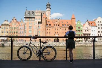 Papier Peint photo Prague Voyageur de la jeune femme avec un vélo rétro près de la rivière dans la vieille ville de gdansk