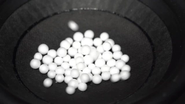 Close-up top view of white polystyrene beads jumping on a working speaker surface by acoustic waves
