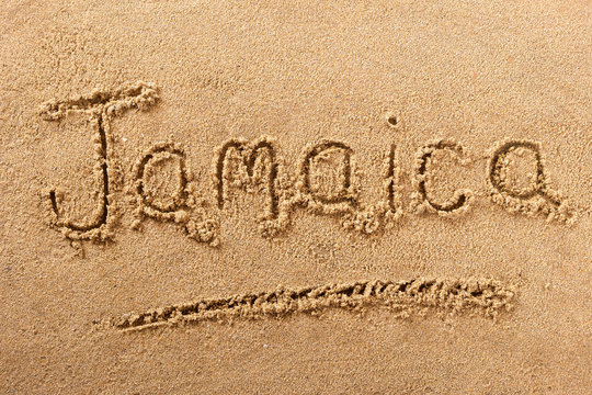 Jamaica word written in sand sign writing drawing drawn on a sunny caribbean summer beach holiday vacation travel destination message photo