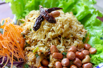 Yam Naem Khao Thot is Spicy Salad of Curried Rice Croquettes, Fermented Pork, Ginger and Peanuts on plate.Thai food