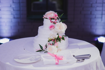 Stylish modern wedding cake. Beautiful dessert decorated with fresh flowers and greenery.