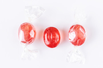 Red cherry oval lollipops on a light paper background. Sweet drops, flat lay, minimalism, top view....