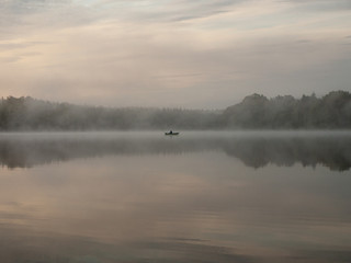 Foggy and mystical lake landscape before sunrise. All silhouettes are blurry and unclear. Vaidavas lake, Latvia