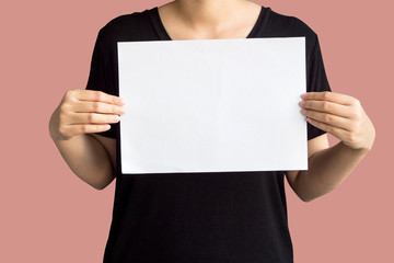 Young woman holding up copyspace Placard.Isolated on pastel pink background