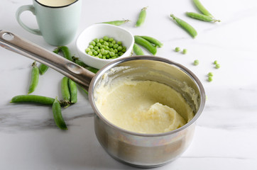 Tasty traditional mashed potatoes with peas on the white kitchen table