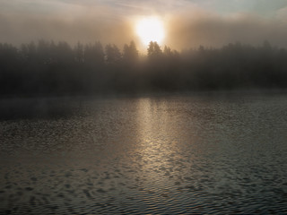 Foggy and mystical lake landscape before sunrise. All silhouettes are blurry and unclear. Vaidavas lake, Latvia