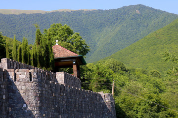 Old stone fortress wall, stone road with an iron fence and peaks of green mountains in Sheki, Azerbaijan