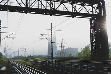 Fototapeta na wymiar railway tracks going into the fog, pipelines and chimneys in the haze