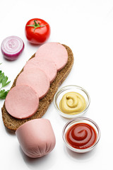 sliced boiled sausage with bread, tomatoes, onion parsley on white background
