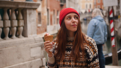 Young woman eating the icecream and looking around on the Venice streets