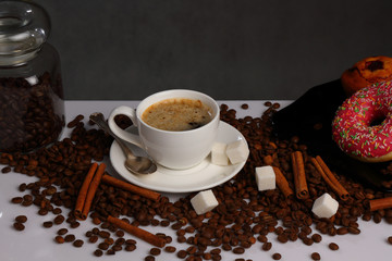 White coffee Cup, coffee beans, cinnamon and donuts