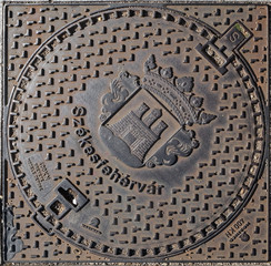 An iron manhole cover in a street of Szekesfehervar, Hungary