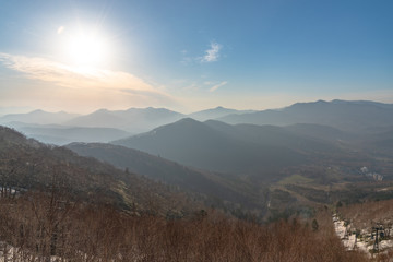 Panoramic view of beautiful mountain landscape, snowy mountain peaks covered by forest with a dark blue clear sky background in spring time sunny day