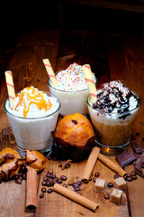 four cups of coffee, americano, cappuccino, late. coffee beans, cinnamon scattered on a wooden table.