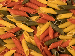 Color penne pasta. Tomato, spinach and wheat pastas as background.
