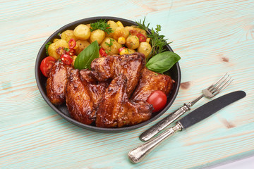 Tasty grilled chicken wings with baked potatoes, Restaurant food, on rustic background