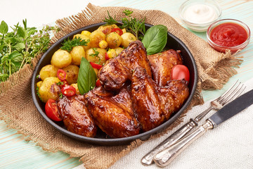 Grilled chicken wings with baked potatoes, Restaurant food, on rustic background