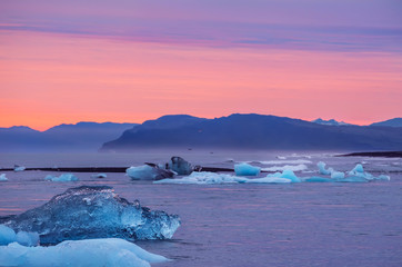 Obraz premium Ice floes on the shore and floating in the water at sunset. Iceland.Long exposure.