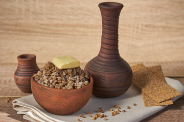 cooked buckwheat with a slice of butter served with rye crisps on wooden table