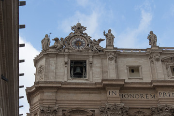 Upper facade of Saint Peter's Basilica seen from Saint Peter's Square with rainy clouds on background, Vatican city state, Italy.