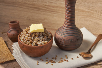 cooked buckwheat with a slice of butter served with rye crisps on wooden table