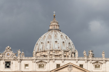 Close up view of St. Peter's Basilica Dome with rainy clouds on background, Vatican city state, Italy.