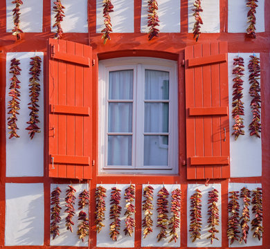 Espelette facade light up by high sun, with typical basque geometric architecture and local peppers hung to dry on facade