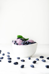 Ice-cream decorated with fresh berries of a honeysuckle and green leaves on white background. Close-up.