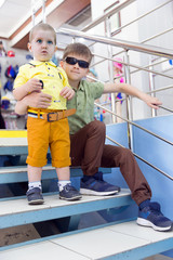 Two brothers posing on the stairs in a clothing store
