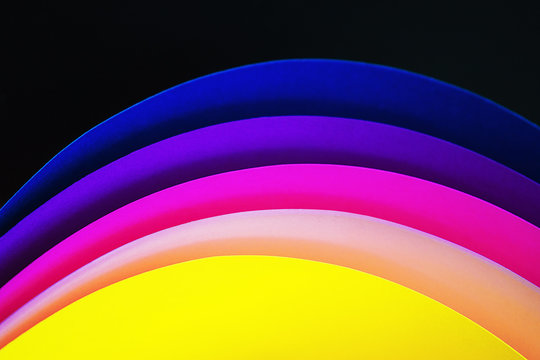 Trendy neon multicolor background from a arcs of cardboard different colors. Copy space. Back to school, party, celebration abstract concept. Minimal style.